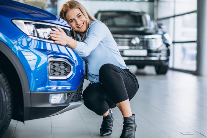a woman leaning on the hood of a blue car protected by ceramic coatings