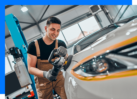 a man polishing a car inside an auto repair and detailing shop